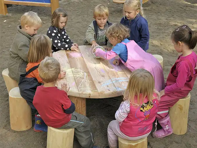 Toddlers drawing with chalks on a wooden table